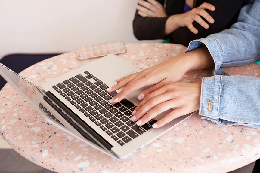 a woman typing on her older macbook pro 864x576